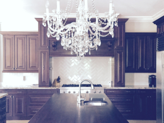 luxury white chandelier over dark wood island and cabinets