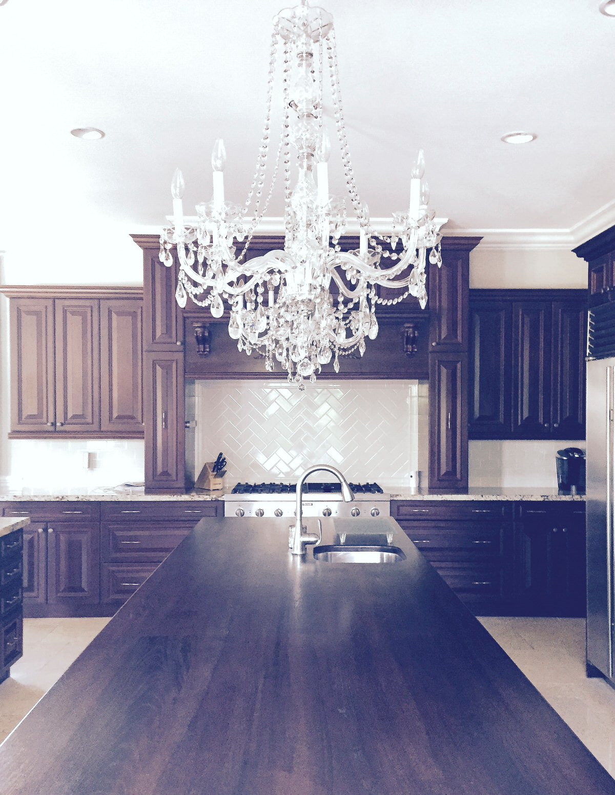 luxury white chandelier over dark wood island and cabinets